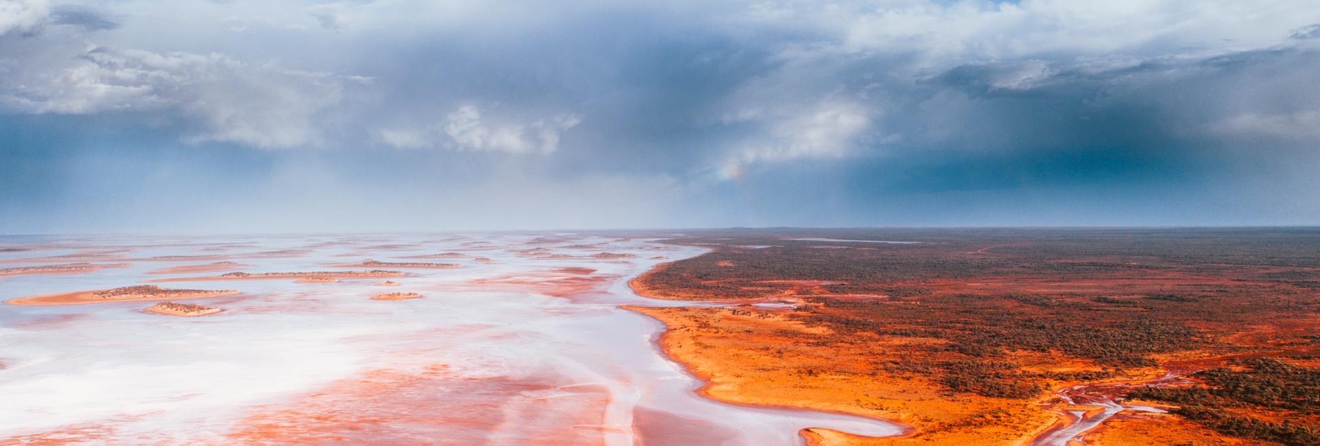 A pink and shimmering salt lake with blue sky and clouds